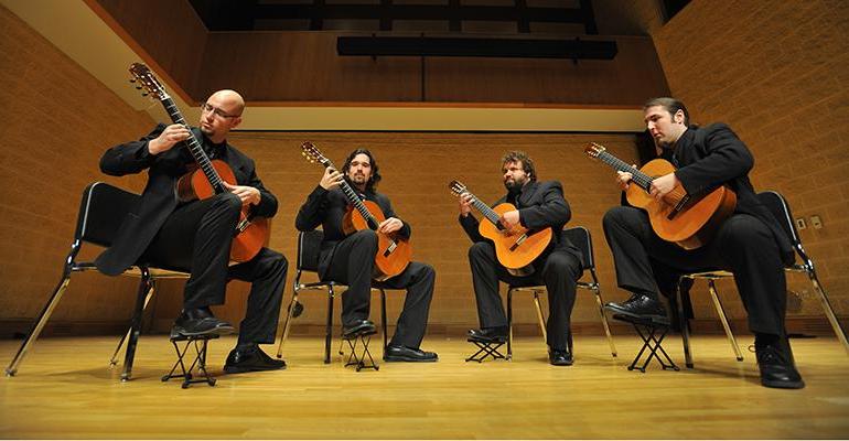 four classical guitarists performing